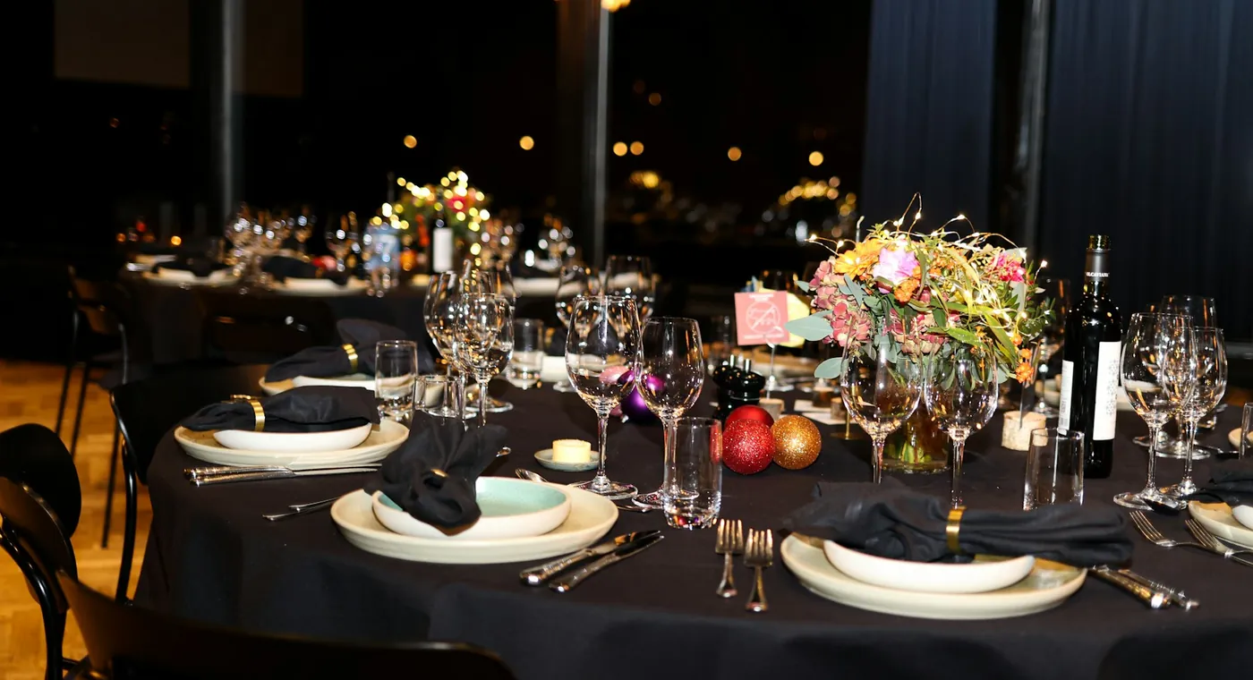 An elegant black-linen banquet table set with gold napkin rings and candlelight
